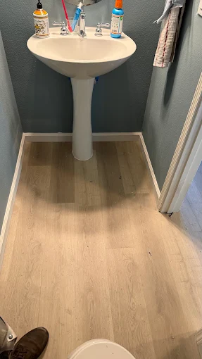Light plank flooring beneath a pedestal sink