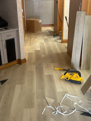 Plank flooring installation in progress beside a fireplace